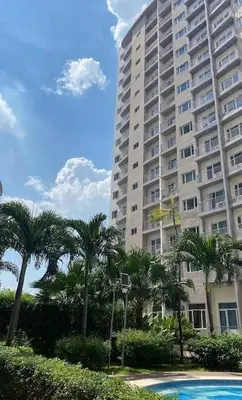 a large apartment building with palm trees in front of it at Furnished Condo Unit-Green2 PoolWifiNetflix in Dasmariñas