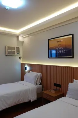a hotel room with two beds and a tv on the wall at YMCA Makati in Manila