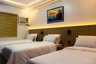 a hotel room with three beds and a picture on the wall at YMCA Makati in Manila