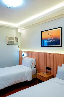 a hotel room with two beds and a tv on the wall at YMCA Makati in Manila