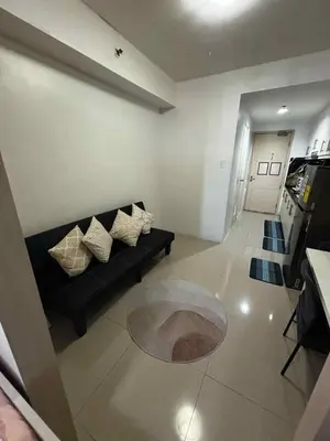 a living room with a black couch and a kitchen at Elizas place in Manila