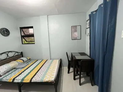 a bedroom with a bed and a table with a desk at RJ Wallfan Studio Transient in Napico, Lifehomes Pasig City in Manila