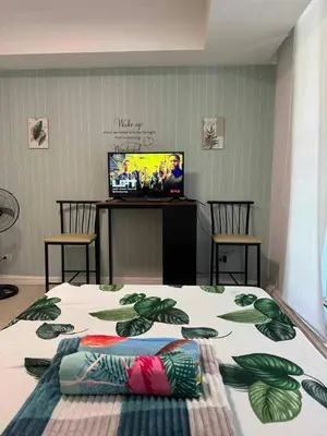 a room with a bed and two chairs and a television at azure 1bedroom pool view in Manila