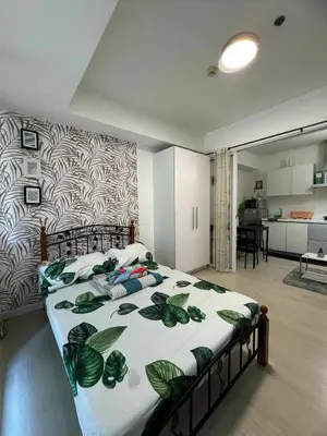 a bedroom with a large bed with a leaf patterned wall at azure 1bedroom pool view in Manila