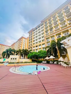 a person in a pool in front of a large building at Unwind Oasis Two Bedroom Free Pool Access in Manila