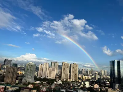 a rainbow in the sky over a city at Breeze Residences pasay near naia airport in Manila