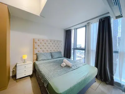a bedroom with a bed and a large window at 1 BR Cozy unit Uptown Parksuites BGC in Manila