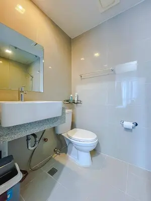 a bathroom with a white toilet and a sink at 1 BR Cozy unit Uptown Parksuites BGC in Manila
