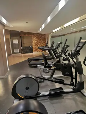 a gym with a row of treadmills and ellipticals at Mall of Asia residence Shore 3 in Manila