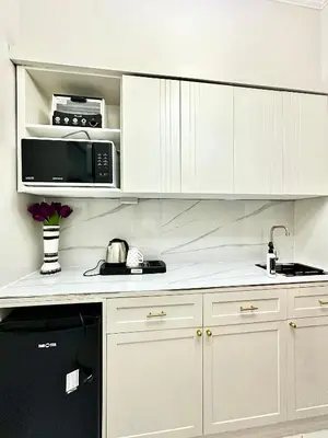 a kitchen with white cabinets and a black appliance at Studio Two Condominium - Olive in Manila