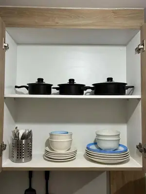 a kitchen shelf with pots and pans and plates at Peaceful Pasay Getaway - Private Studio with Pool in Manila