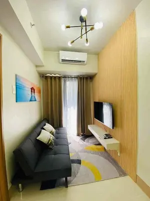 a living room with a black couch and a television at Shore Residence 3 tower 1 Amenity view MOA Terminal 3 in Manila