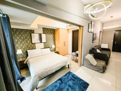 a bedroom with a bed and a living room at Charming 1BR in Uptown Parksuites Tower 2 BGC in Manila