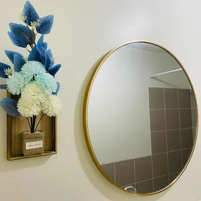a mirror on a wall with a vase of blue and white flowers at V-TAN house in Manila