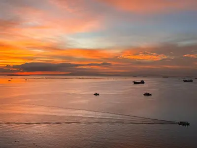 a sunset on a beach with boats in the water at Luxury 2BR Condo Retreat Near Airports MOA Okada in Manila