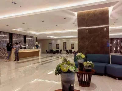 a lobby with a blue couch and people in a building at Cozy Coast Residences Pasay in Manila