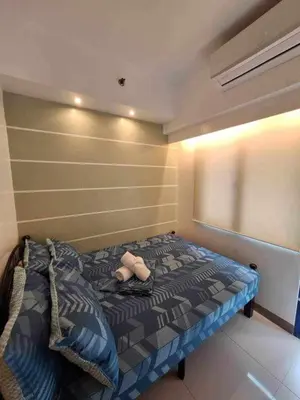 a bedroom with a bed with a stuffed animal on it at Sea Residences MOA Oasis-Nicolai Ramos in Manila