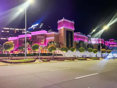 a large building with pink lights on it at night at Elegant 2 Bedroom Suite near Solaire, Okada in Manila