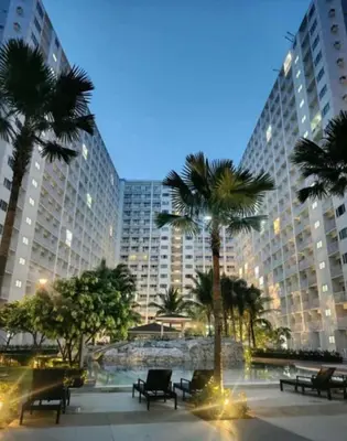 a large building with palm trees in front of it at Staycation near MOA, Airport in Manila