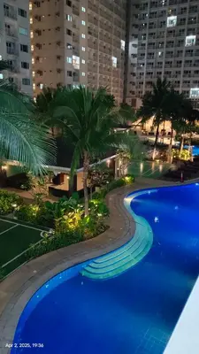 a large blue swimming pool with palm trees and buildings at Shore Residences Tower D # 408 in Manila