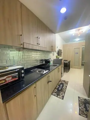 a kitchen with wooden cabinets and a black counter top at Shore Residences Tower D # 408 in Manila