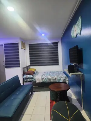 a bedroom with a bed and a couch and a table at El Cozy Woody Near Enchanted Kingdom in Santa Rosa