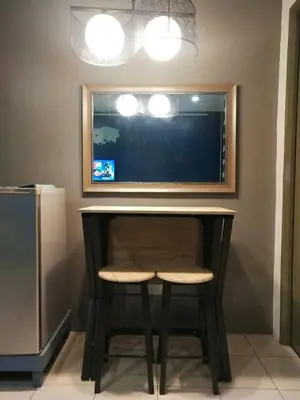a desk with a stool and a tv on a wall at El Cozy Woody Near Enchanted Kingdom in Santa Rosa