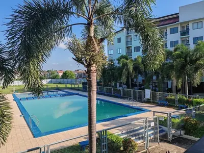 a swimming pool with a palm tree in front of a building at El Cozy Woody Near Enchanted Kingdom in Santa Rosa