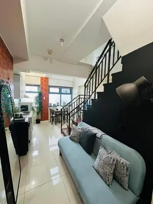 a living room with a blue couch and a staircase at Newly Renovated 2-storey Loft at Greenbelt 1 Near Legaspi Park in Manila