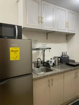 a kitchen with a refrigerator and a sink at 2 Bedroom with Massage Chair 15 minutes from NAIA in Manila