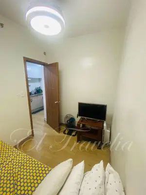 a living room with a bed and a television at 2 Bedroom with Massage Chair 15 minutes from NAIA in Manila