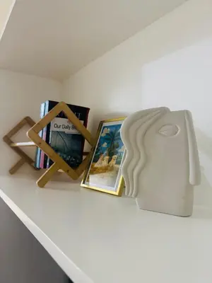 a shelf with books and a white vase on it at Berkeley Breeze Staycation in Silang