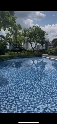 a blue tile swimming pool with trees in the background at Fully-furnished 1-br unit in Manila