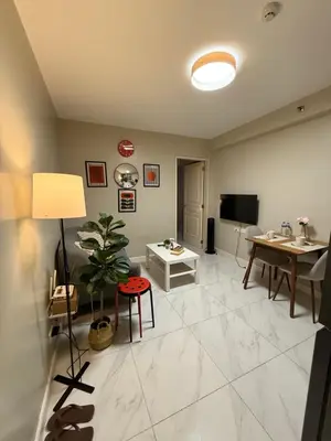 a living room with a table and a television at Bayhaus MNL - Pet-friendly Condo near MOA in Manila