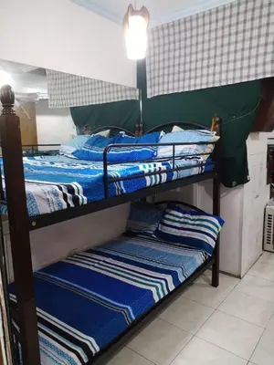 two bunk beds with blue and white striped sheets at male bedspace in Manila