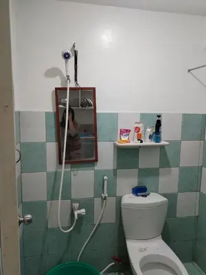 a bathroom with a toilet with a mirror and a shower at male bedspace in Manila