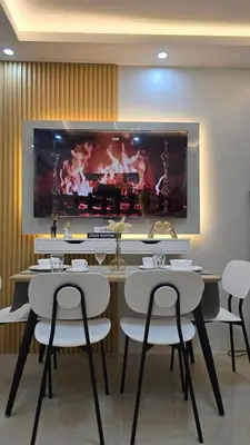 a dining room with white chairs and a large painting on the wall at Sevillano's City Escape at Shore 1 Near MOA in Manila