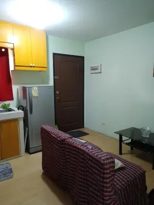 a living room with a couch and a kitchen at One Oasis Ortigas H212 in Manila