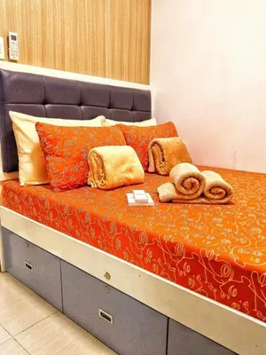 a bed with orange pillows and towels on it at DS Staycation in Manila