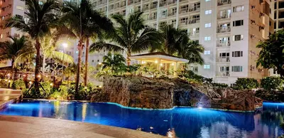 a resort pool with a waterfall in front of a building at Balay Maria at Shore in Manila