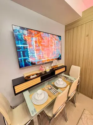 a dining room with a table and a flat screen tv at Shore Staycation in Manila