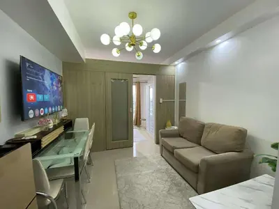 a living room with a couch and a chandelier at Shore Staycation in Manila