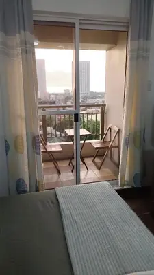 a bedroom with a bed and a balcony with a view at Windsong Suite Unli Netflix Disney Roofdeck View in Manila