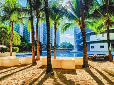 a group of palm trees on a beach with a building at 1BR Unit Azure Urban Resort Residences in Manila