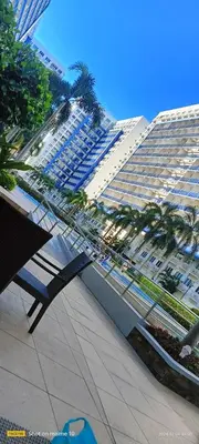 a bench in front of a large building with palm trees at Sea Residences Yanah Staycation in Manila