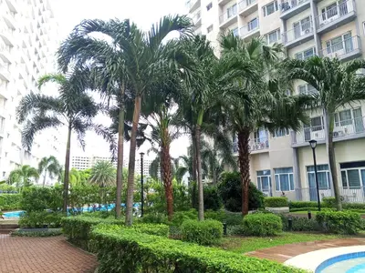 a row of palm trees in front of a building at Casa Solana at SMDC South Residences in Manila