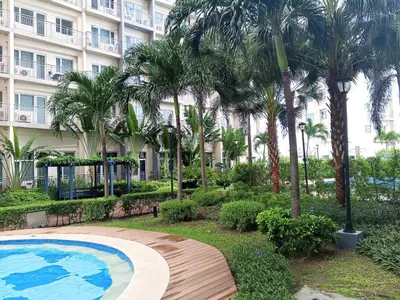 a pool in front of a building with palm trees at Casa Solana at SMDC South Residences in Manila