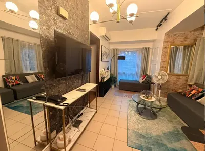 a living room with a couch and a tv at Forbeswood Parklane Condominium in Manila