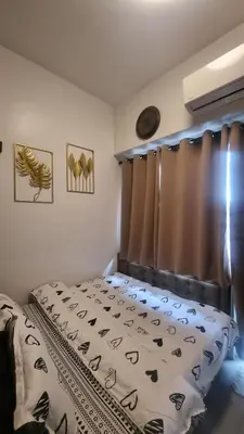 a bedroom with a bed and a window with curtains at The C Place Mla in Manila