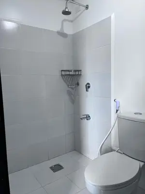 a white bathroom with a toilet and a shower at Cozy Nook in the City in Manila